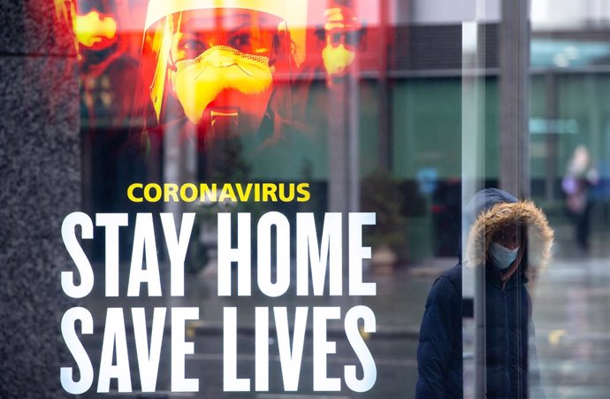 14 January 2021, England, London: A woman walks past a government conronavirus 'stay home, save lives' advert in central London during England's third national lockdown to curb the spread of coronavirus. Photo: Dominic Lipinski/PA Wire/dpa