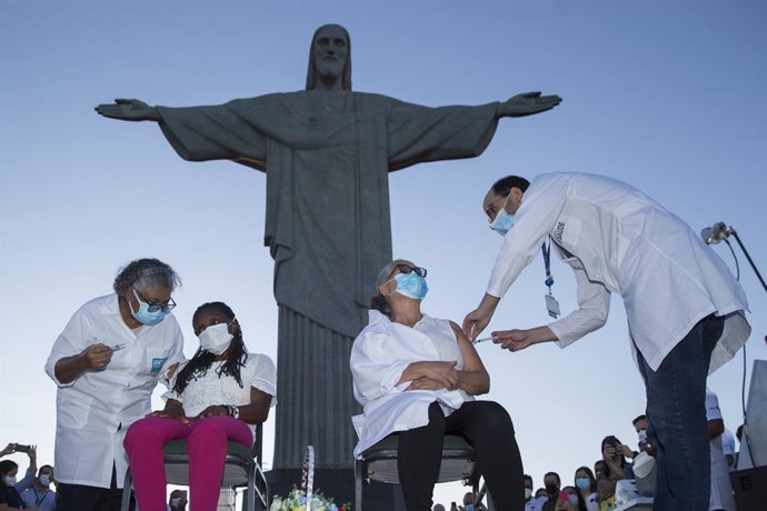 18 January 2021, Brazil, Rio de Janeiro: Two women receive coronavirus (Covid-19) vaccine during a vaccination campaign in front of the Christ the Redeemer statue. Photo: Fernando Souza/dpa