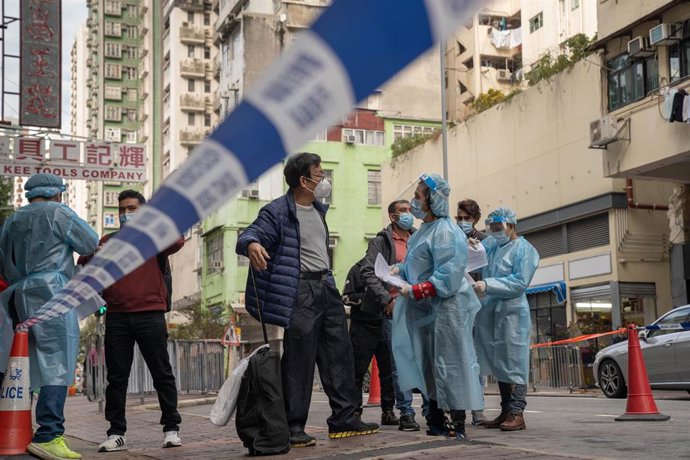 Un grupo de trabajadores sanitarios de Hong Kong ofrece información a un grupo de vecinos que acuden a hacerse la prueba obligatoria de coronavirus.