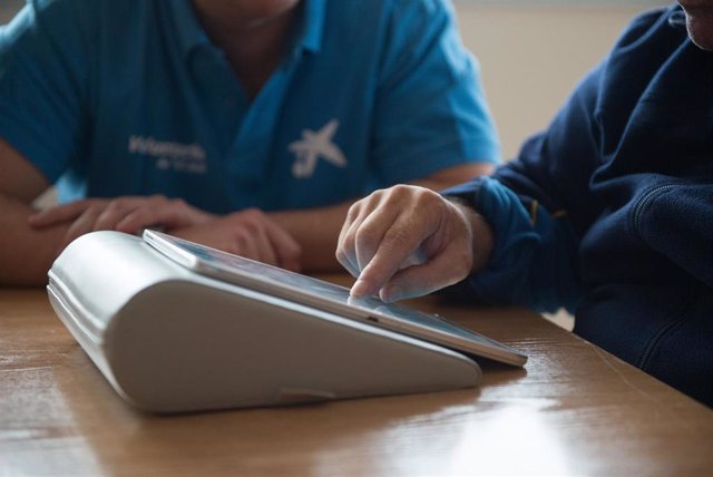 Voluntaria “la Caixa” forma a una persona en el uso de tablets para comunicarse con sus familiares.