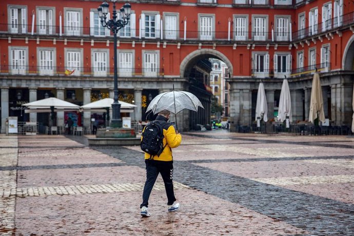 Un hombre camina protegido por un paraguas el mismo día de la llegada del temporal Gaetán, en la Plaza Mayor de Madrid, (España), a 20 de enero de 2021. El temporal de nieve y posterior frío provocado por la borrasca 'Filomena' terminó ayer para dejar