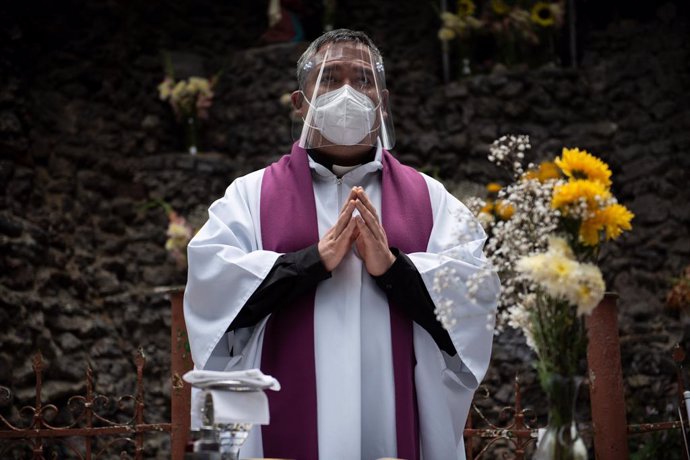 15 January 2021, Bolivia, La Paz: A priest wears a face shield and a mask prays during a service held outdoors at Hospital de Clinicas for health care workers who died from Covid-19. Photo: Radoslaw Czajkowski/dpa