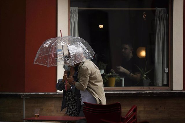 Dos personas se protegen de la llovizna bajo un paraguas durante el aviso amarillo activado por la Agencia Estatal de Meteorología (Aemet)