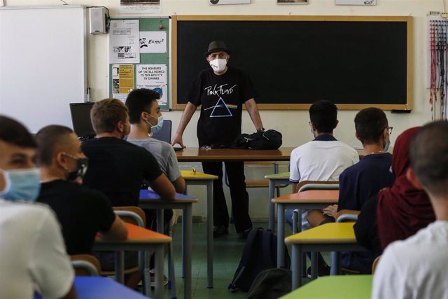 Un profesor y sus alumnos con mascarilla en una clase de un instituto en Roma