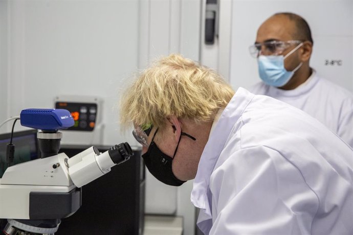 18 January 2021, United Kingdom, Oxford: UK Prime Minister Boris Johnson wearing a face mask looks at a microscope in the quality control laboratory, where batches of Coronavirus vaccine are tested, during a tour of the manufacturing facility for the Ox