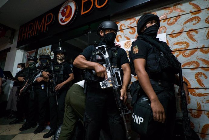 02 March 2020, Philippines, Manila: S.W.A.T. police officers hide behind a building as they prepare to tackle hostage taker Archie Paray. Police surrounded a shopping mall in the Greenhills district of Manila after Archie Paray, a recently dismissed sec