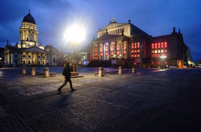 15 January 2021, Berlin: A passer-by walks across the otherwise deserted Gendarmenmarkt. The German Chancellor Angela Merkel and Minister Presidents of the federal states are to discuss further measures to contain the coronavirus pandemic on 19 January 