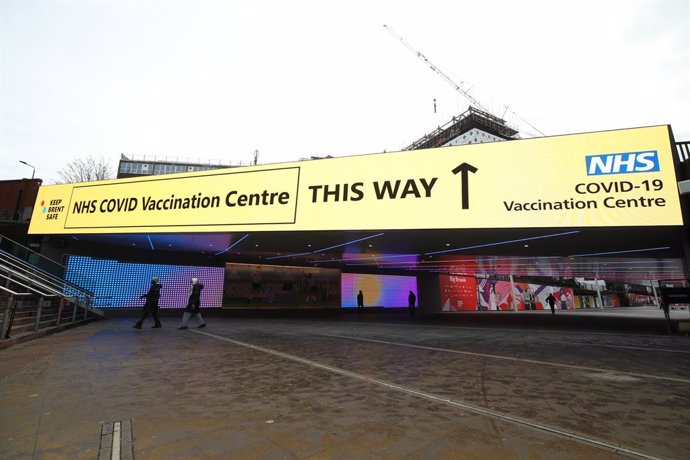 18 January 2021, United Kingdom, London: An information sign outside Wembley station gives direction to the National Health Service (NHS) Corona vaccination centre at the Olympic Office Centre in Wembley, as ten further mass vaccination centres open in 