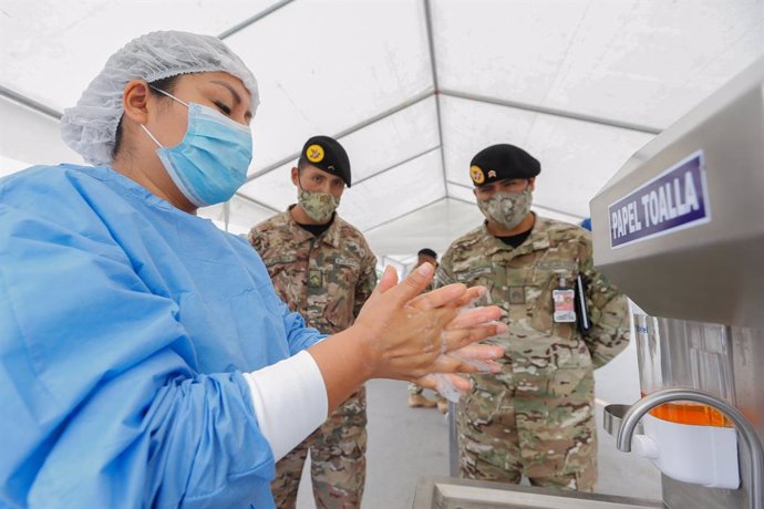 HANDOUT - 15 December 2020, Peru, Lima: A health worker shows soldiers how to wash and disinfect their hands. Armed forces will support health personnel in the Coronavirus vaccination campaign. Photo: Karel Navarro/Minsa/dpa - ACHTUNG: Nur zur redaktion