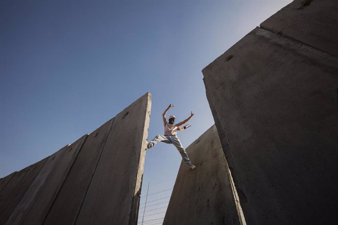 Palestino sobre una brecha del muro de Cisjordania en Ramala