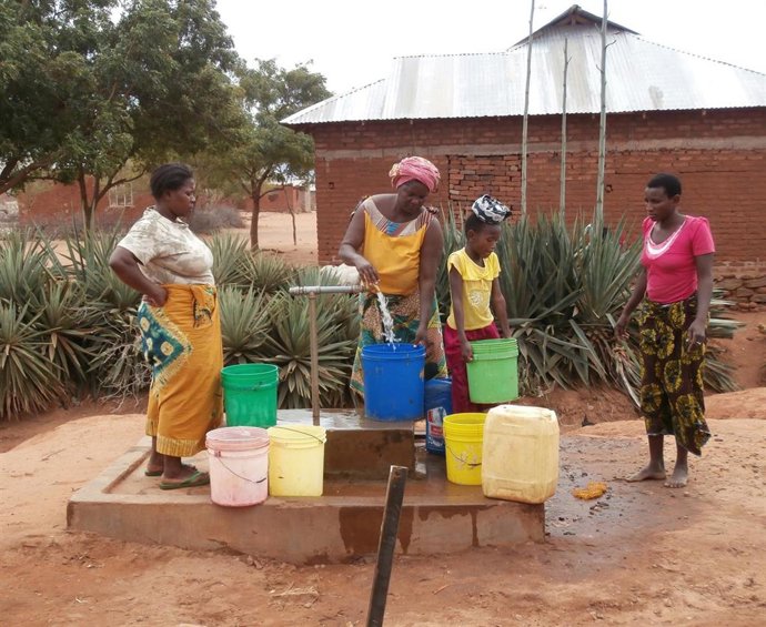 Varias personas llenan bidones de agua.