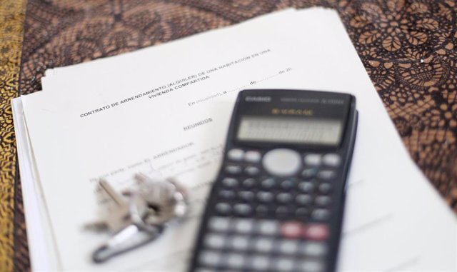 Una calculadora y unas llaves sobre un contrato de arrendamiento de una habitación en una vivienda compartida.