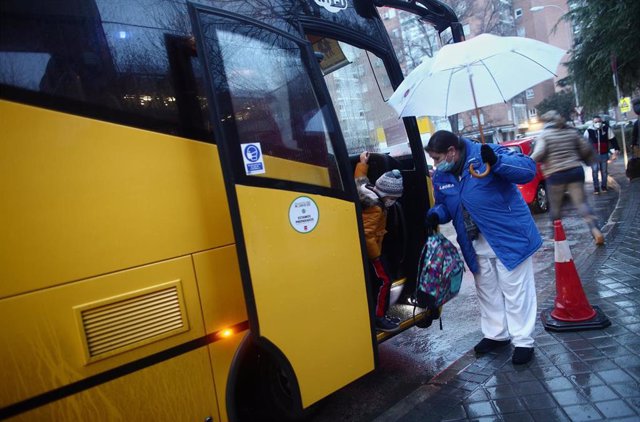 Una trabajadora ayuda a bajar a un alumno de un autobús escolar del colegio Arcangel Rafael el día de la reapertura de los centros educativos tras la gran nevada registrada por el paso de Filomena, en Aluche, Madrid, (España), a 20 de enero de 2021. E