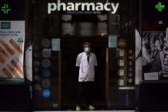 Un farmacéutico protegido con mascarilla en la puerta de una farmacia durante el segundo día laborable del estado de alarma por el coronavirus, en Barcelona (España), a 17 de marzo de 2020.