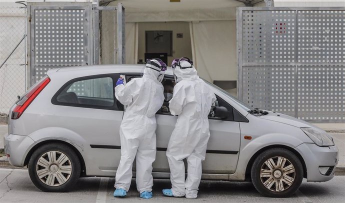 Dos sanitarios realizan una prueba PCR a una persona desde su vehículo para la detección del coronavirus