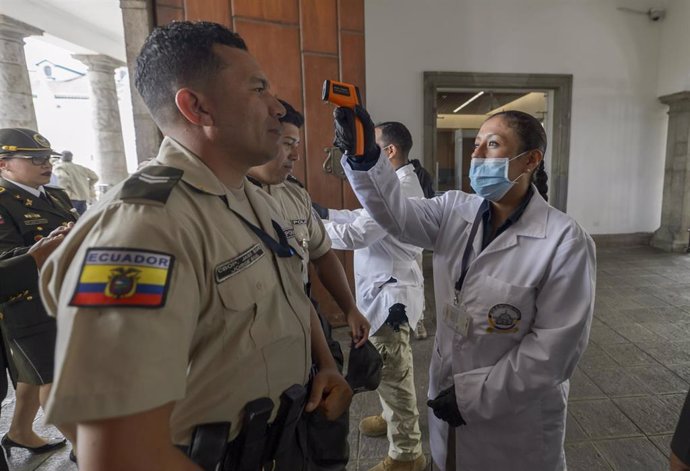 Personal médico comprueba la temperatura de varios agentes de la Policía de Ecuador, en medio de la crisis sanitaria de la COVID-19.