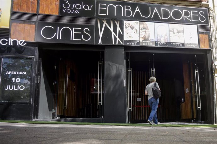 Una mujer pasa por la puerta de los Cines Embajadores el día en el que abre sus puertas tras el parón por el coronavirus, en Madrid (España), a 10 de julio de 2020. Durante su reapertura se proyecta la película 'Cinema Paradiso'.