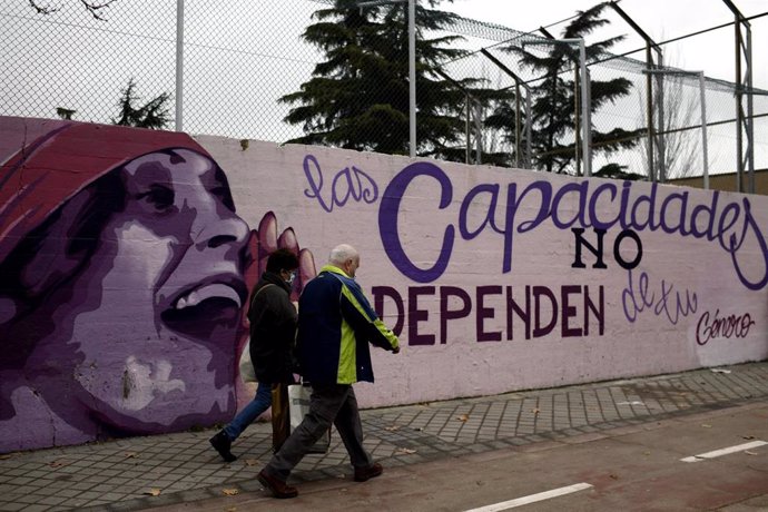 Dos personas pasan por el mural feminista en el polideportivo municipal de la Concepción en el distrito de Ciudad Lineal 