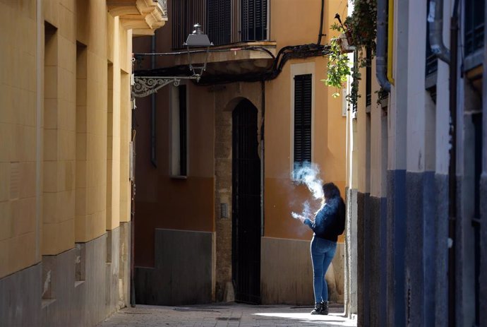 Una mujer fuma en una calle desierta en Palma.