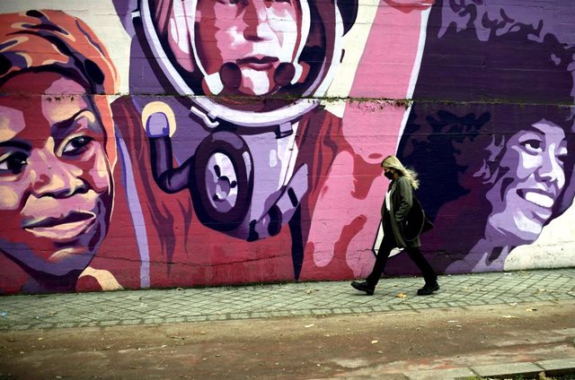 Una mujer pasa por el mural feminista en el polideportivo municipal de la Concepción en el distrito de Ciudad Lineal 