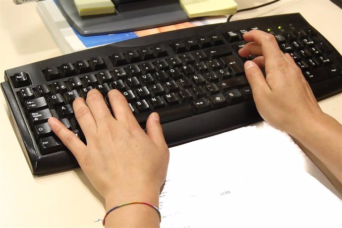 Un trabajador escribiendo en un teclado de ordenador.