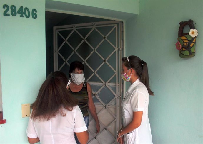 Estudiantes de medicina cubanos preguntan a una mujer en La Habana sobre posibles síntomas de covid-19