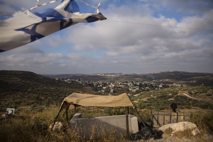 Un soldado israelí observa la aldea palestina de Kfar Kadum mientras custodia el asentamiento judío de Har Hemed cerca de Nablus, en Har Hemed, Cisjordania.