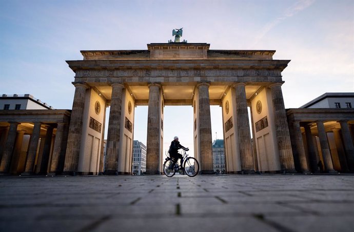 17 December 2020, Berlin: A woman rides his bicycle across the empty March 18 Square at the Brandenburg Gate amid a nationwide lockdown that came into force on Wednesday to tackle the surging numbers of new coronavirus cases. Photo: Kay Nietfeld/dpa
