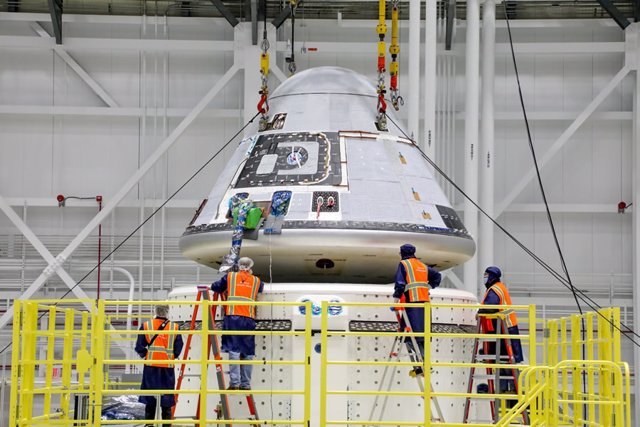 Los técnicos observan que el módulo de tripulación Starliner de Boeing se coloca encima del módulo de servicio en la instalación de procesamiento de carga y tripulación comercial en el Centro Espacial Kennedy de la NASA en Florida el 14 de Enero de 2021
