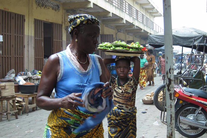 Una niña porta una bandeja con alimentos sobre la cabeza en Cotonou (Benín)