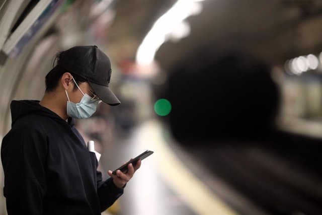 Un joven mira su móvil mientras espera la llegada del metro en la estación de Estrecho