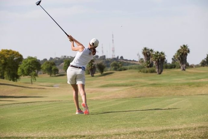Una jugadora practica en un campo de golf