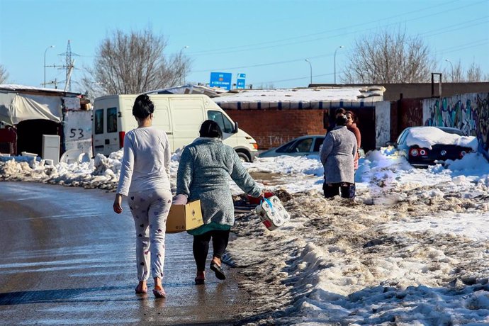 Dos vecinas de la Cañada caminan con alimentos y productos de primera necesidad repartidos por una furgoneta de Cruz Roja.