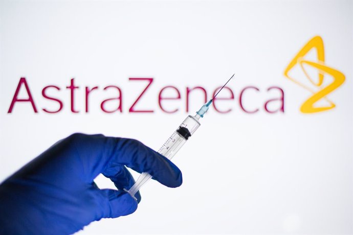 26 January 2021, Spain, Barcelona: A person holds a syringe in front of the AstraZeneca logo. The chief executive of pharmaceutical giant AstraZeneca fended off EUallegations about a drastic downsizing in planned deliveries of Covid-19 vaccine, while t