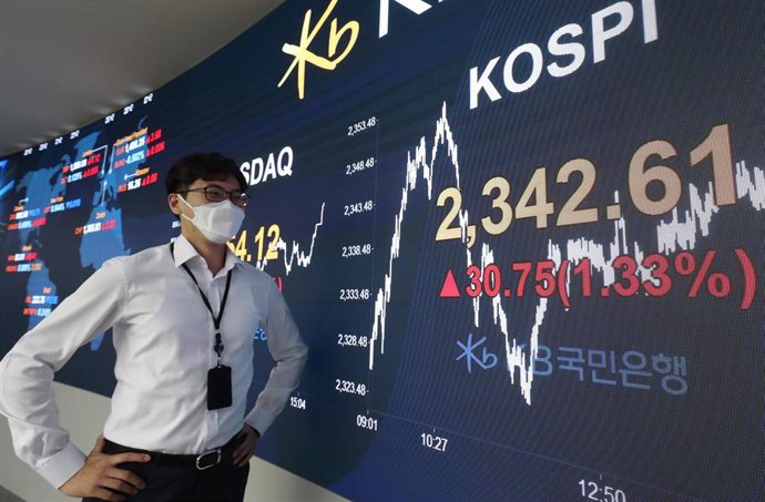 06 August 2020, South Korea, Seoul: A currency trader stands in front of an electronic signboard in the dealing room of KB Kookmin Bank, which shows the benchmark Korea Composite Stock Price Index (KOSPI) rising as it closed. Photo: -/yonhap/dpa