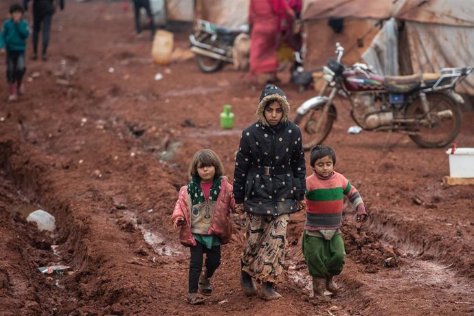 Niños sirios desplazados caminan sobre barro en el campamento de Marabune en Idlib, Siria.