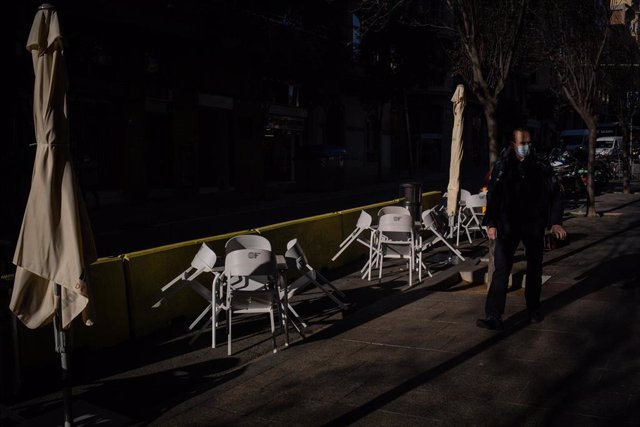 Un hombre pasa al lado de las sillas vacías de una terraza en Barcelona.