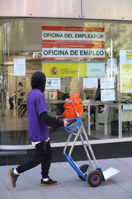 Un joven pasa con una carretilla por una oficina de empleo de Madrid.