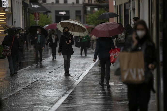 Varias personas con paraguas en una calle céntrica. Lluvias débiles y temperaturas suaves durante la jornada de hoy en Sevilla (Andalucía, España), a 25 de enero de 2021.