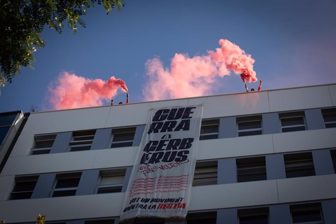 Algunas personas encienden botes de humo y despliegan una pancarta en el terrado del edificio de la sede de Haya Real State, inmobiliaria del fondo de inversión Cerberus, en Barcelona.