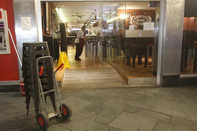Un camarero recoge las mesas de la terraza de un bar en Palma.