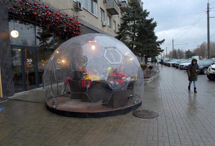 25 January 2021, Ukraine, Dnipro: People sit at the table under a glass cupola of a winter terrace opened in one of the city restaurants, Dnipro, east-central Ukraine. Photo: -/Ukrinform/dpa