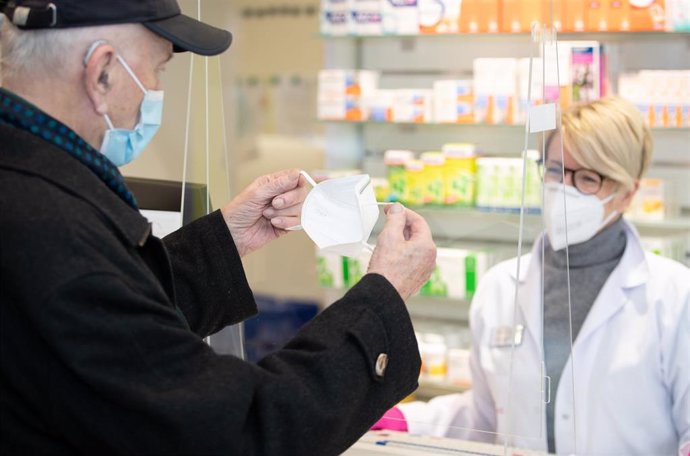  North Rhine-Westphalia, Bielefeld: An elderly man receives an FFP2 mask from Pharmacist Nadine Sallach.