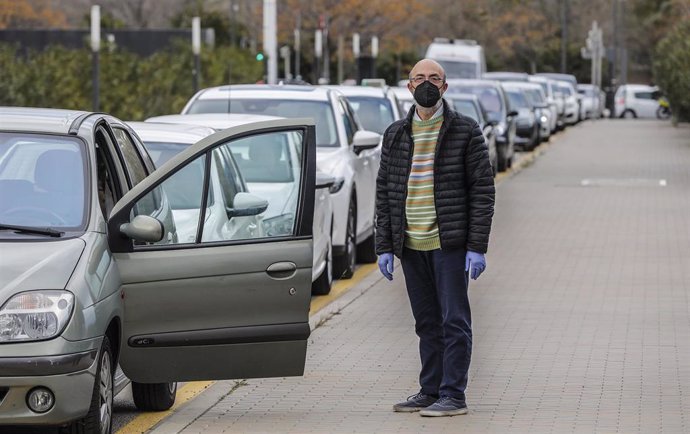 Un hombre espera fuera de su vehículo para realizarse una prueba PCR
