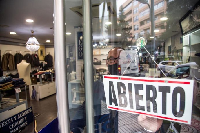 Un comercio muestra en su puerta un cartel donde se lee "abierto" 
