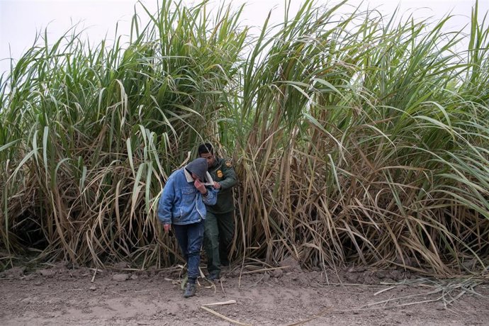 Un guardia fronterizo detiene a un hombre en la frontera con México.