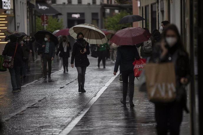 Varias personas con paraguas en una calle céntrica. 