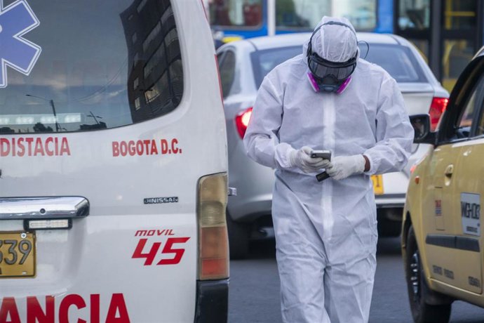 Un trabajador sanitario consulta el teléfono en Bogotá.