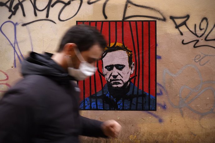 25 January 2021, Italy, Rome: A man wears a face mask as he passes past by a poster made by the street artist Harry Greb depicting the Russian opposition leader Alexei Navalny in the downtown of the city of Rome. Photo: Vincenzo Livieri/ZUMA Wire/dpa