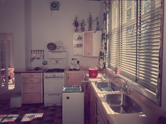 Circa 1955:  A fully fitted kitchen, complete with stove, washing machine, double sink unit and electric mixer.
